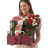 Woman holds festive gift basket with red roses, holiday treats, and Christmas decor.