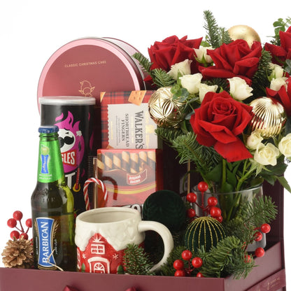 Red roses, festive treats, and holiday decor in a rich burgundy gift basket.