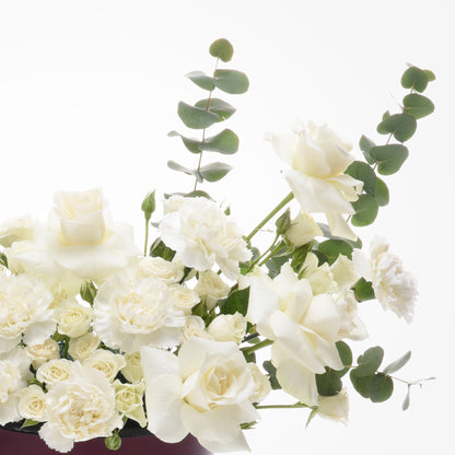 Elegant white roses and eucalyptus in minimalist floral arrangement.