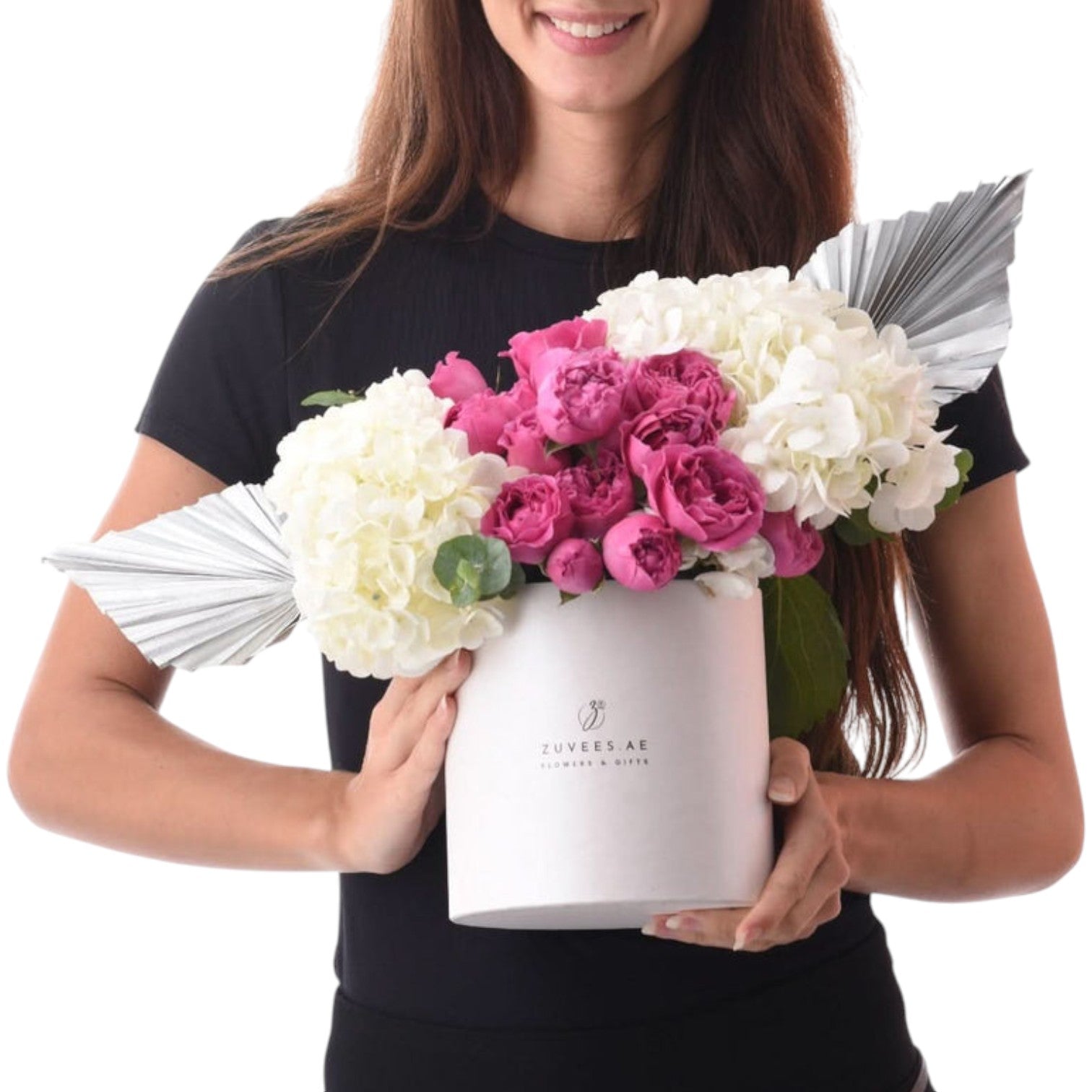 White cylindrical vase holds vibrant pink peonies and white hydrangeas, accented with silver fan embellishments.