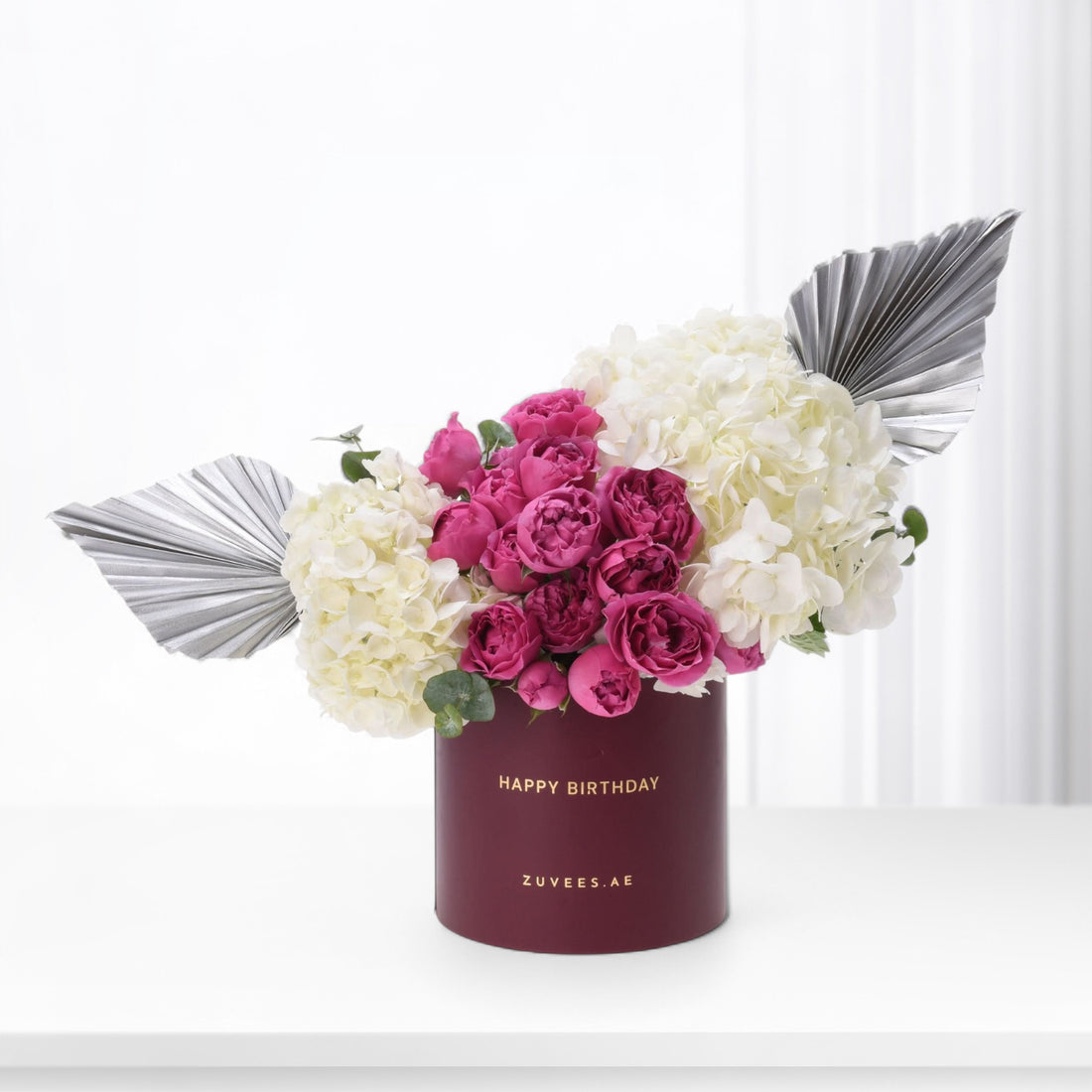 Elegant burgundy box with "Happy Birthday," vibrant pink roses, creamy hydrangeas, and metallic silver fan accents.