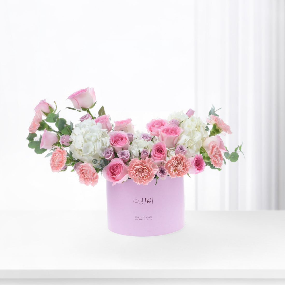 Pastel pink roses, carnations, and hydrangeas in a lavender box.