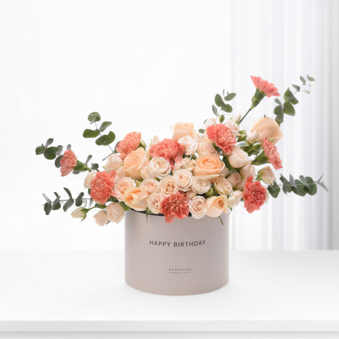 Pastel peach roses and carnations in minimalist box with "Happy Birthday" text.