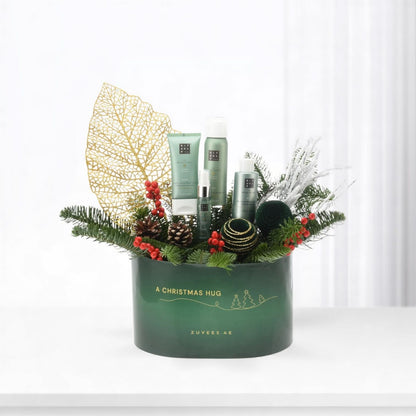 Green "A Christmas Hug" gift box with Rituals products, pine, berries, gold leaf, festive ornaments.