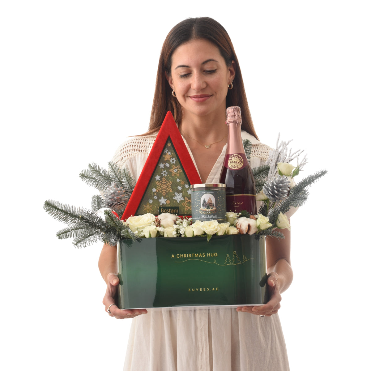 Green gift box with rose champagne, white roses, and festive pine.