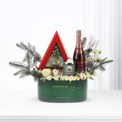 Emerald green holiday gift basket with champagne, candles, and festive white florals.