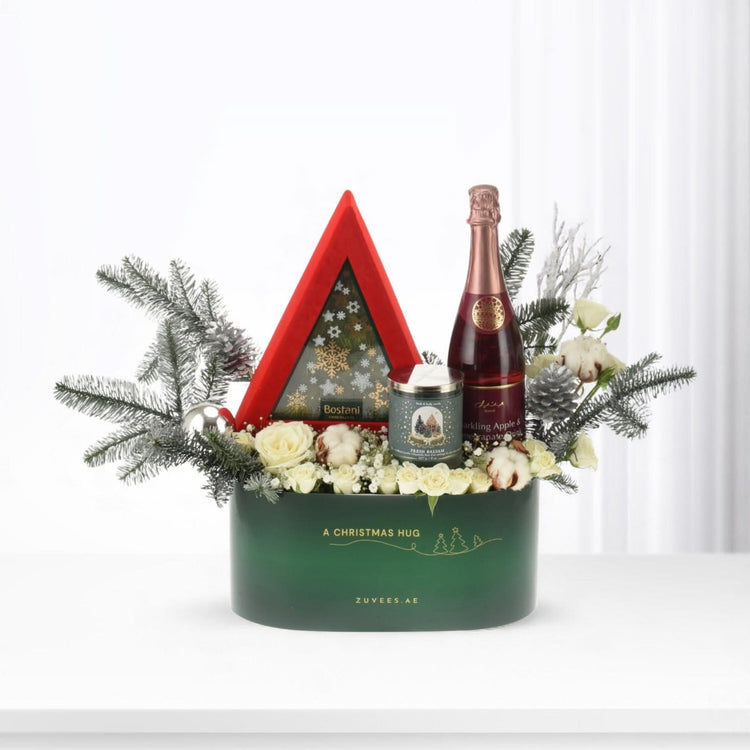 Emerald green holiday gift basket with champagne, candles, and festive white florals.