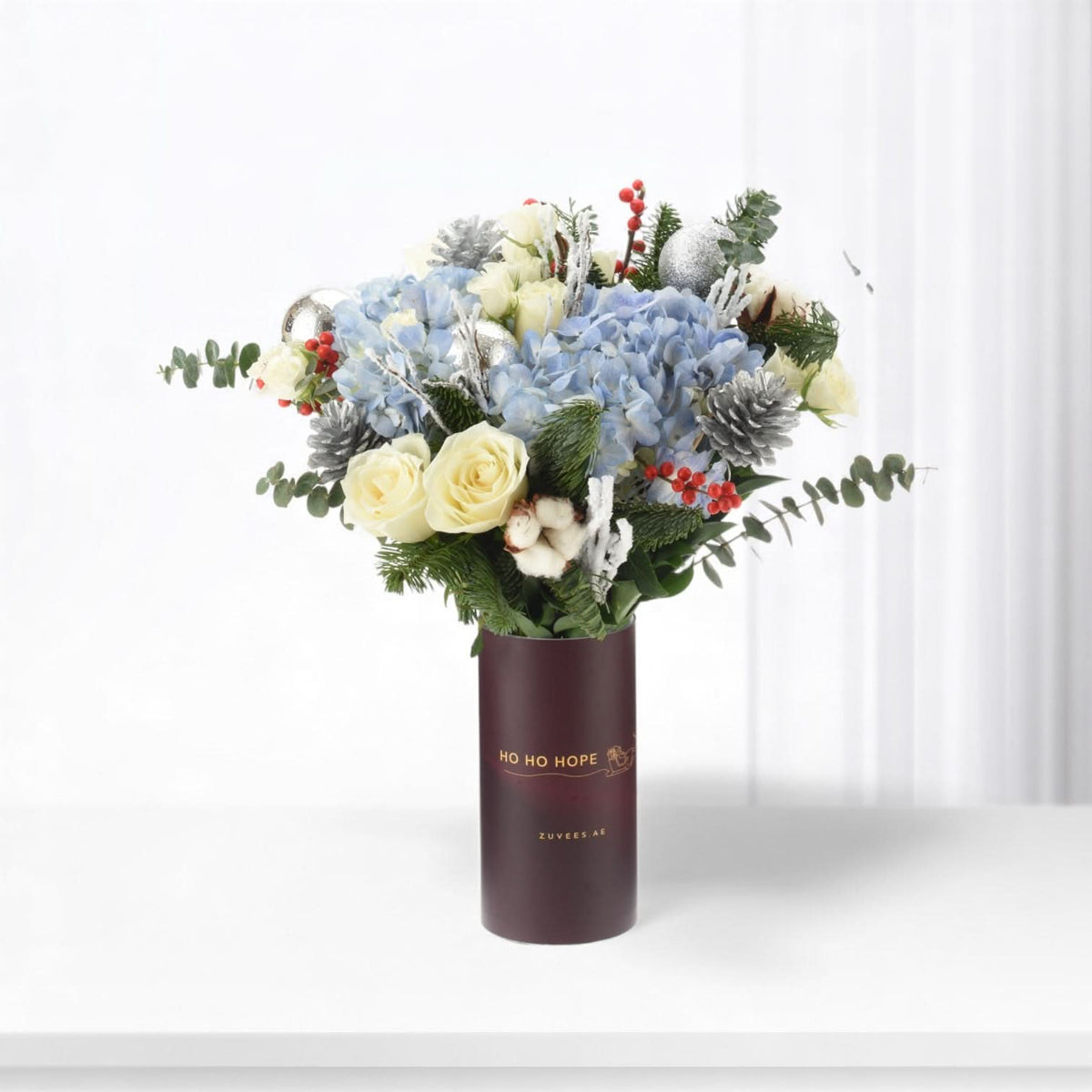Elegant winter bouquet in burgundy vase with "HO HO HOPE" text.