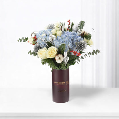 Elegant winter bouquet in burgundy vase with "HO HO HOPE" text.