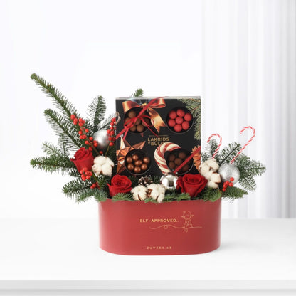 Red gift box adorned with pine, roses, candy canes, and silver ornaments.