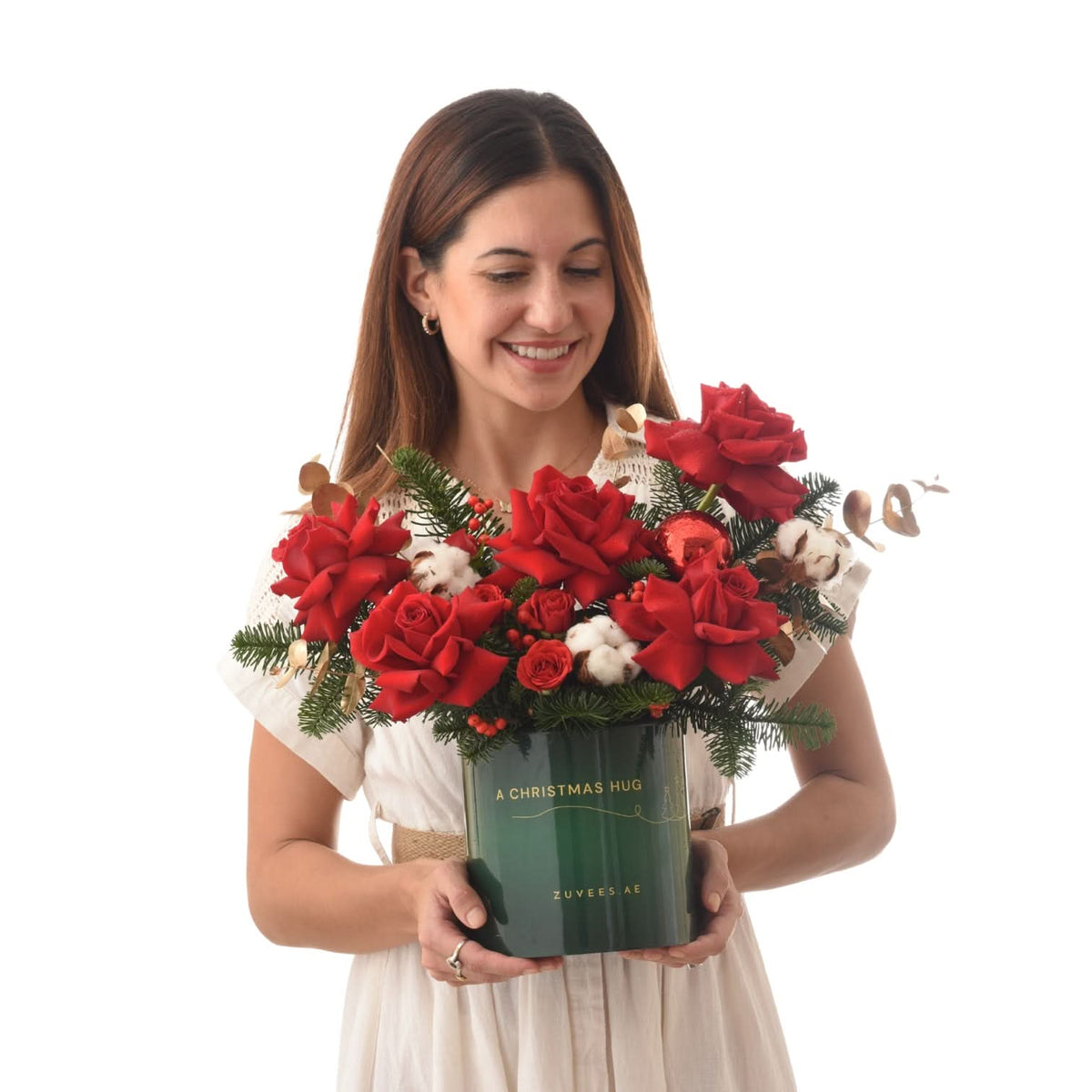 Woman holds festive red rose bouquet in green "Christmas Hug" box.