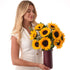 Woman holds vibrant sunflower bouquet in sleek burgundy vase.