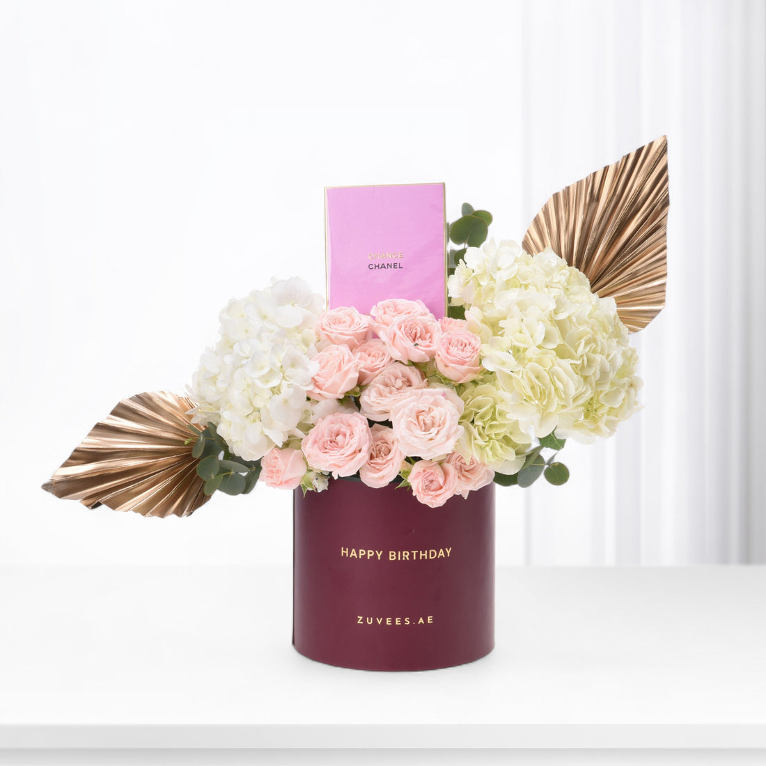 Elegant birthday bouquet in burgundy box with pink roses, hydrangeas, and gold accents.
