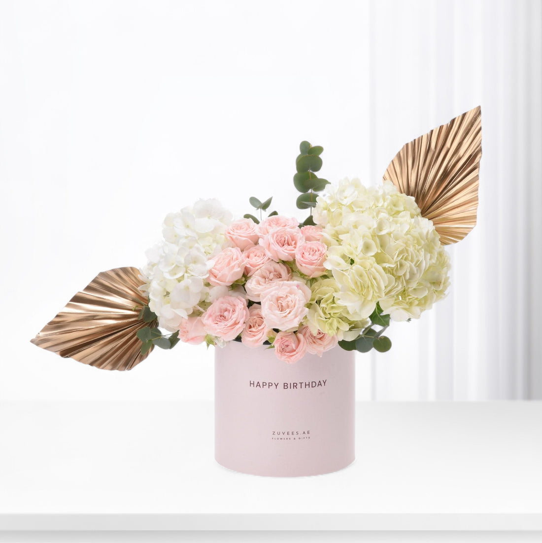 Pink roses and hydrangeas in blush box with gold leaf accents.