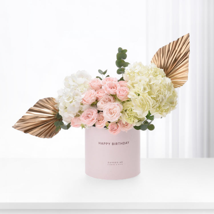 Pink roses, white hydrangeas, gold leaves in blush "Happy Birthday" box, elegant gift.
