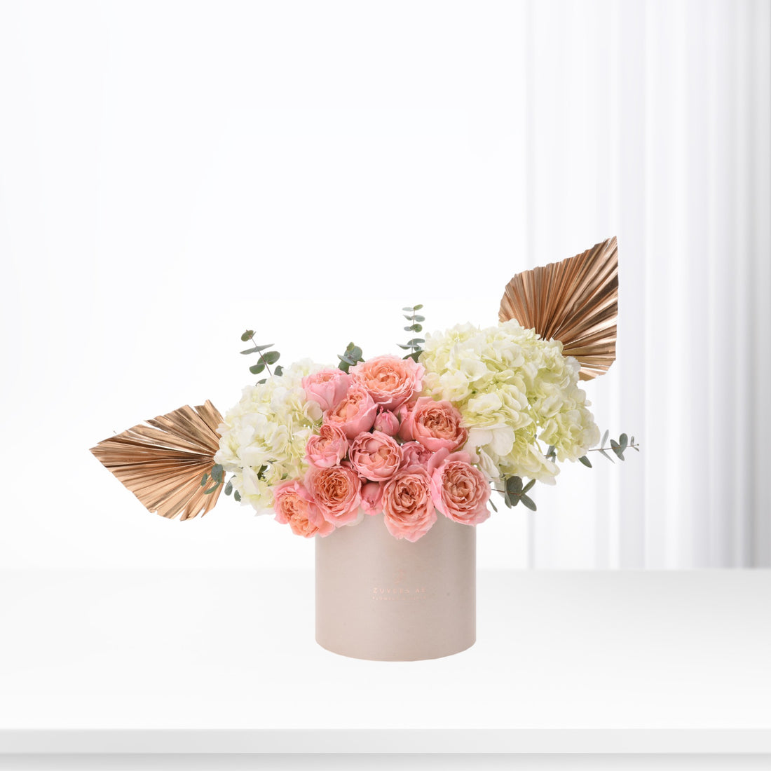 Elegant pastel floral arrangement with gold accents in minimalist container.