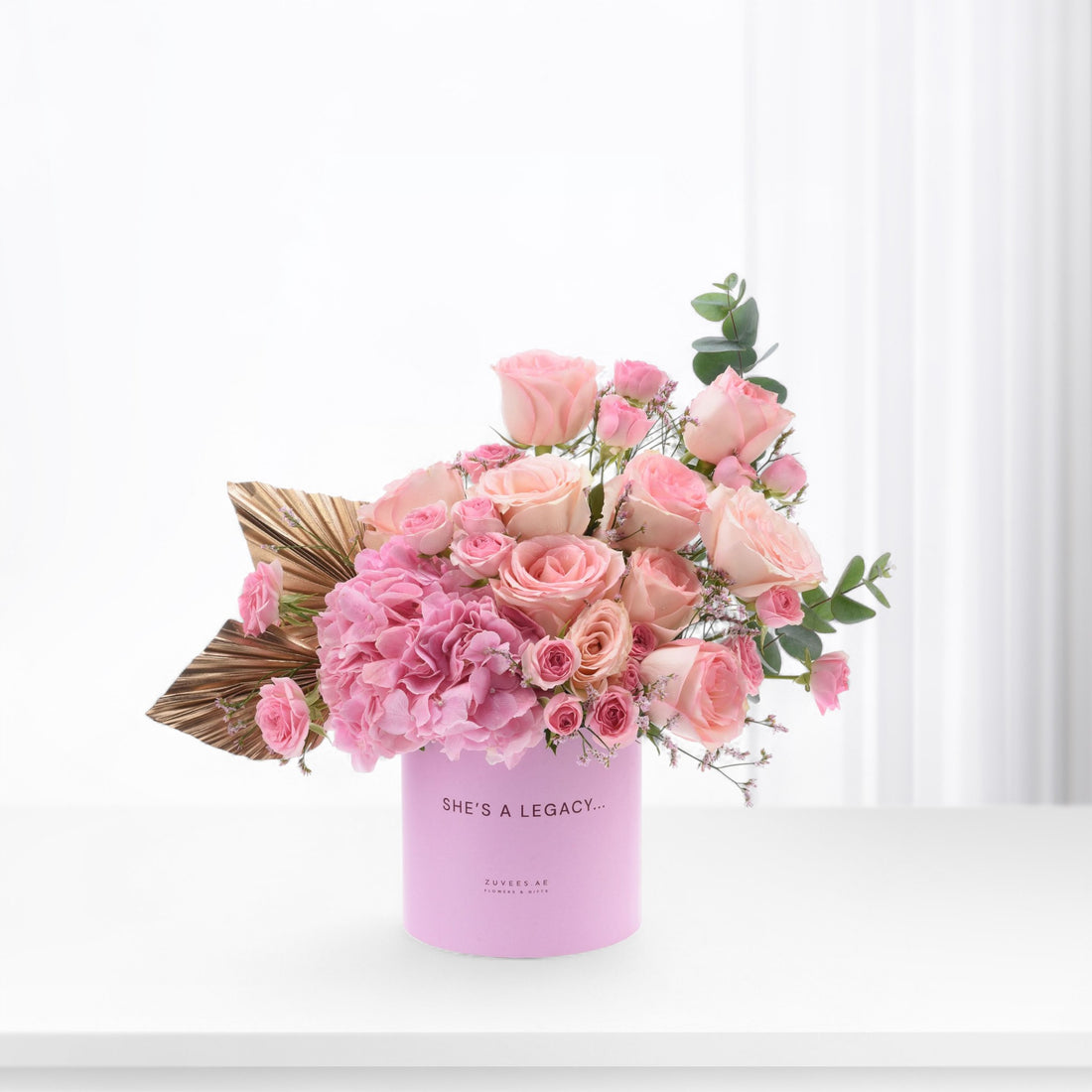 Soft pink roses and hydrangeas in lavender cylinder with gold leaf accent.