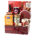 Festive gift basket with wine, snacks, mug, and red ribbon, perfect for holiday gifting.