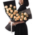 Elegant woman holds peach rose bouquet in sleek black wrap with white ribbon.