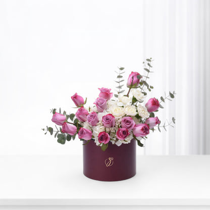 Elegant burgundy box holds vibrant pink roses and white blooms with eucalyptus.
