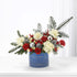 Vibrant red and cream blooms with pine, silver ornaments, and festive blue container.