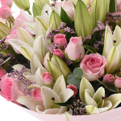 Soft pink roses and white lilies nestled in pastel pink wrapping.