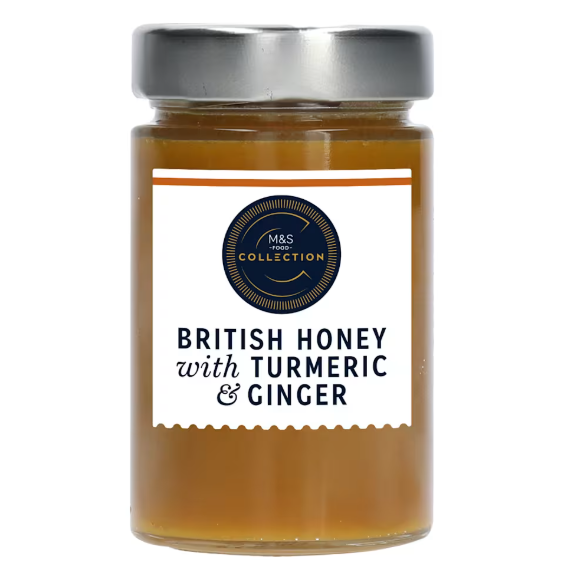 Clear glass jar of M&amp;S British honey with turmeric &amp; ginger, amber liquid, silver lid, navy label.