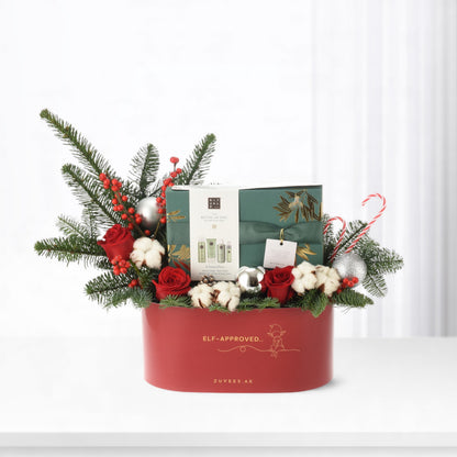 Red holiday gift basket with greenery, red roses, and silver ornaments.