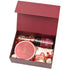 Rich burgundy gift box holds sparkling drink, cookies, Raffaello, and festive candy house.