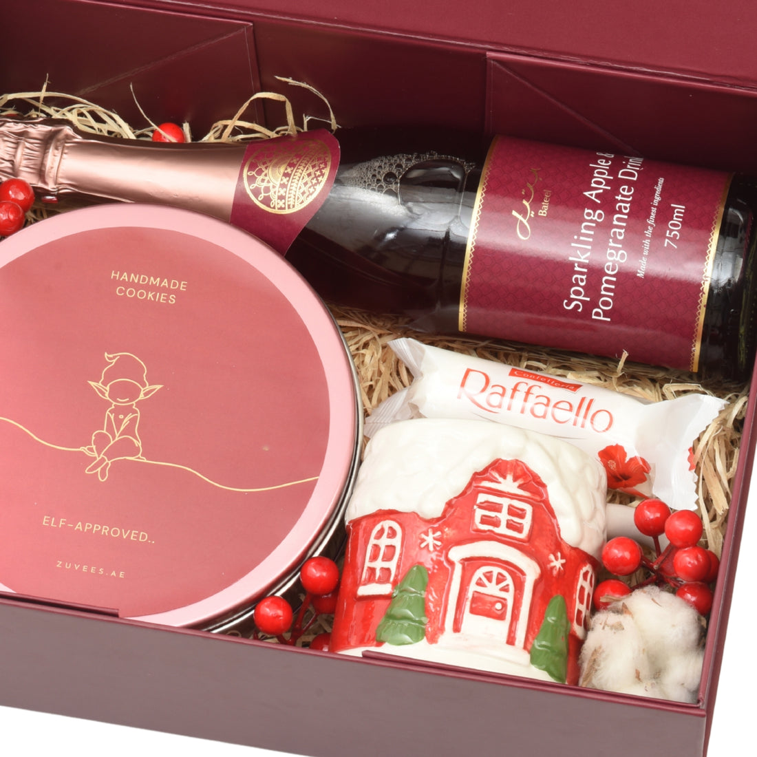 Luxury holiday gift box with festive treats, sparkling drink, and red berry accents.