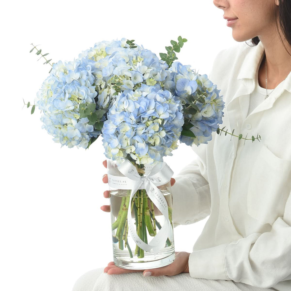Woman holding a vase of deep blue hydrangeas, flower delivery in Dubai