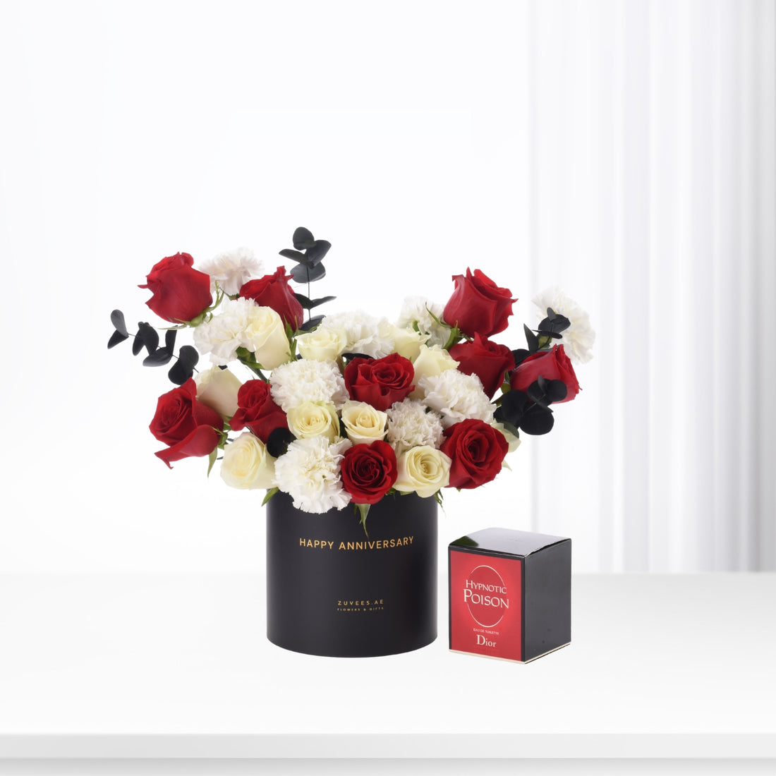 Bold red, white roses and black eucalyptus in sleek black vase with "Happy Anniversary" and Dior perfume.