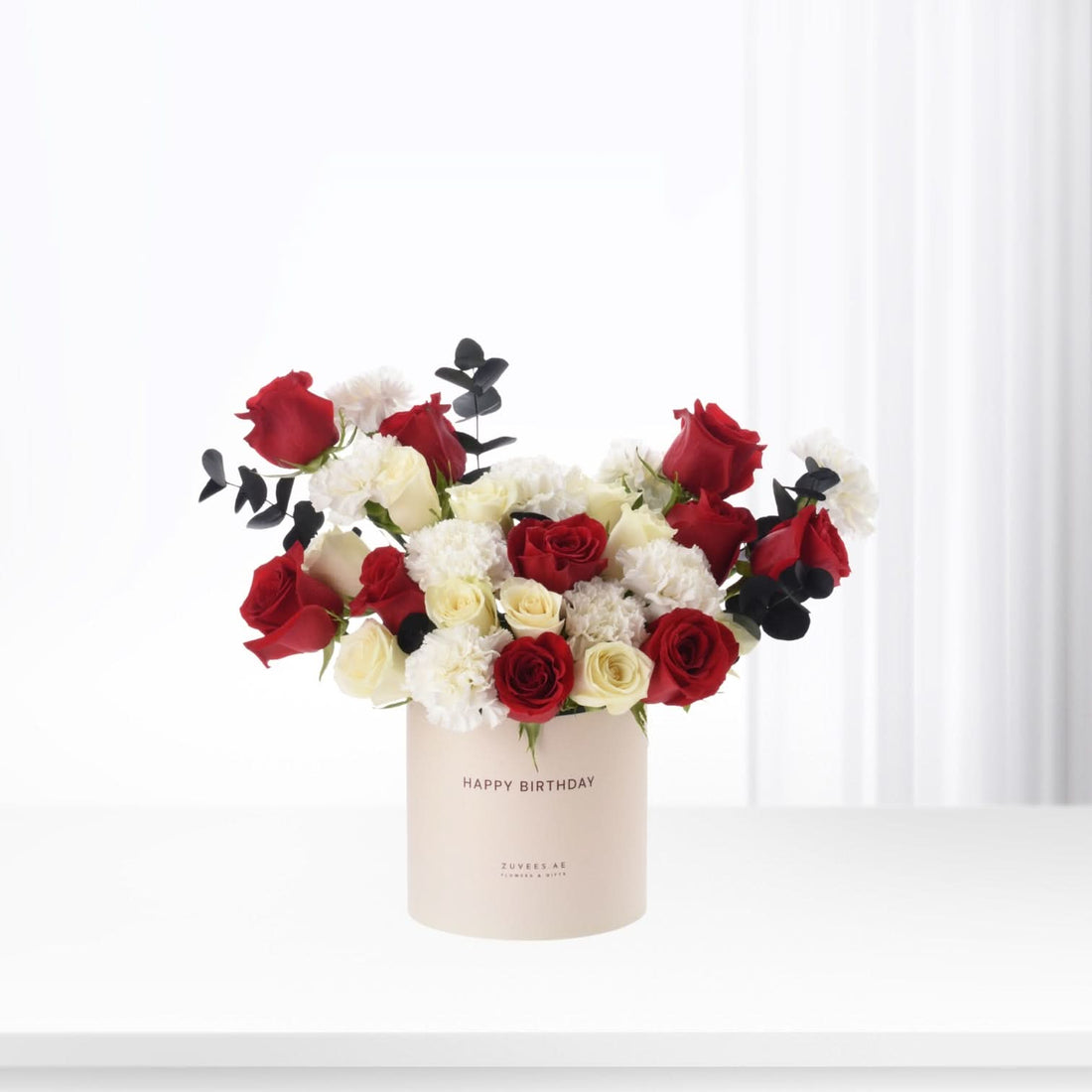 Red and white roses with black eucalyptus in beige "Happy Birthday" box.