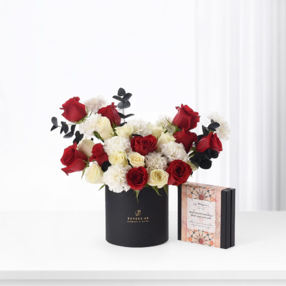 Elegant red and white roses with eucalyptus in black Zuvees box, paired with spice caramel gift.