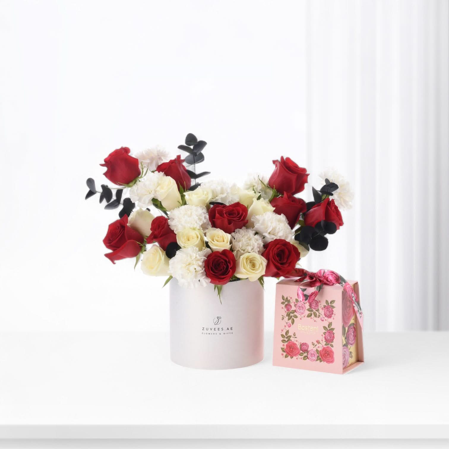 Elegant red and white rose bouquet in matte pink cylinder with floral gift box.