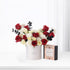 Elegant red, white roses and carnations in minimalist white box beside spice caramel gift.