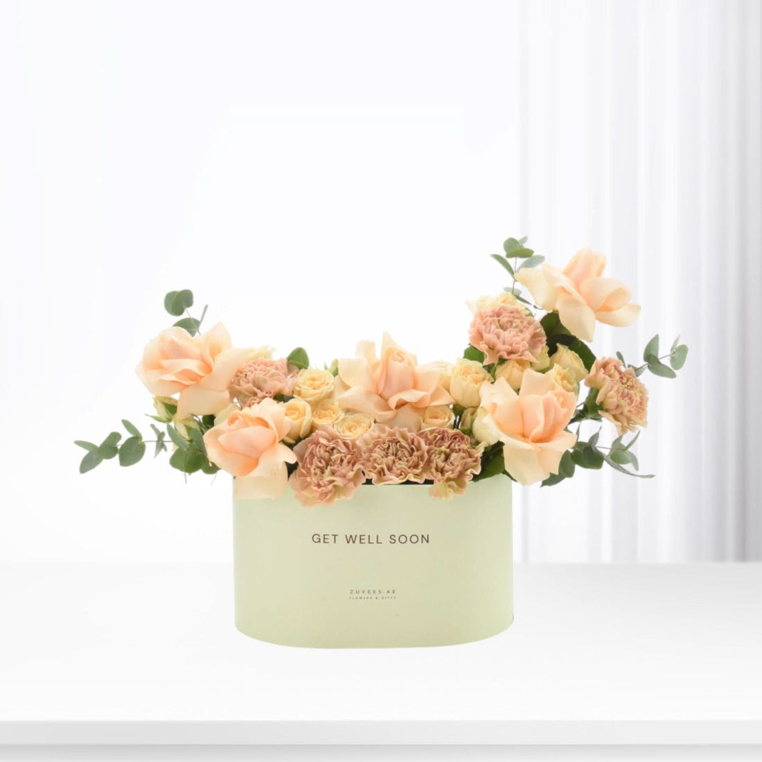 Pastel peach roses and carnations in mint box reading "Get Well Soon".