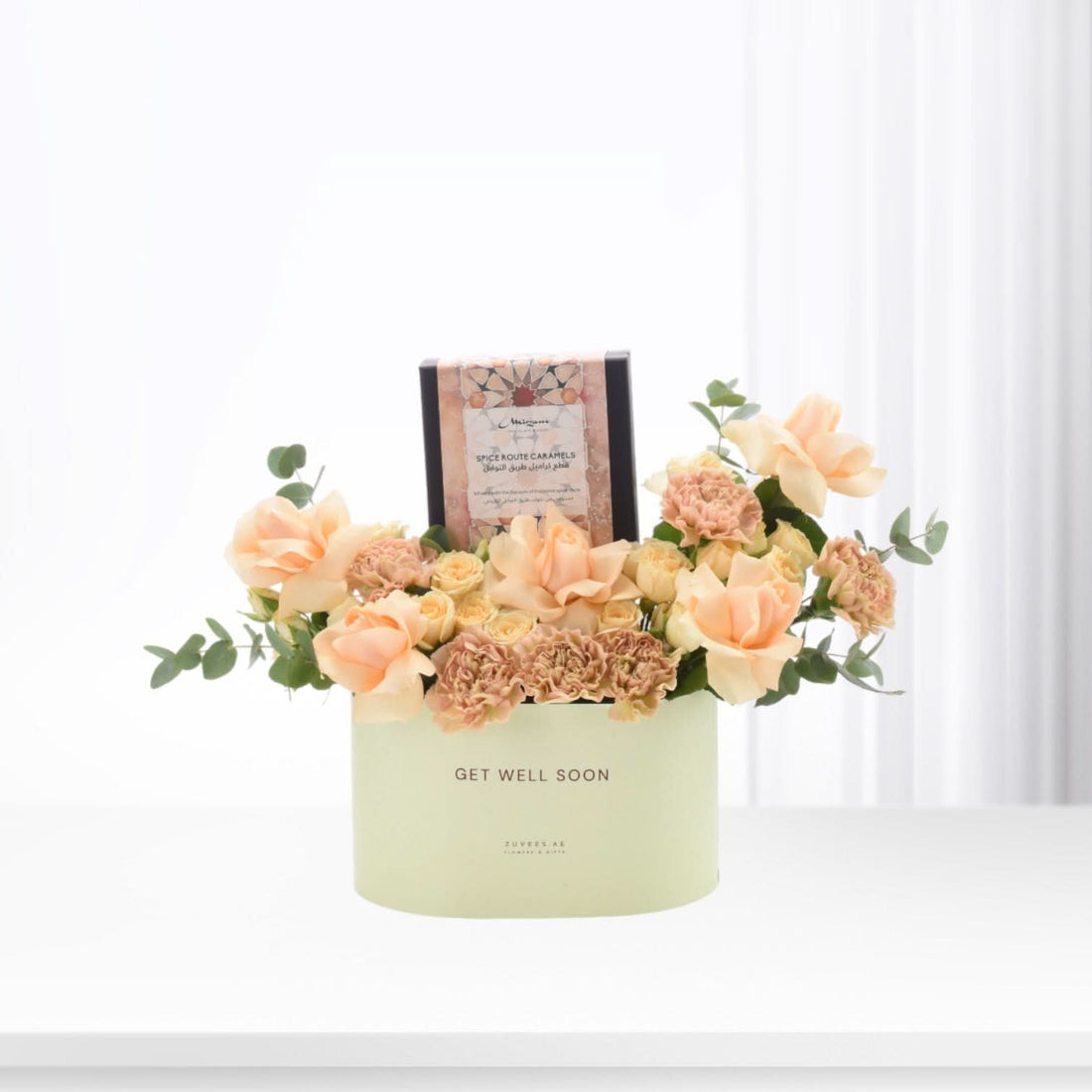 Pastel peach roses and carnations in mint-green "Get Well Soon" box with caramel gift.