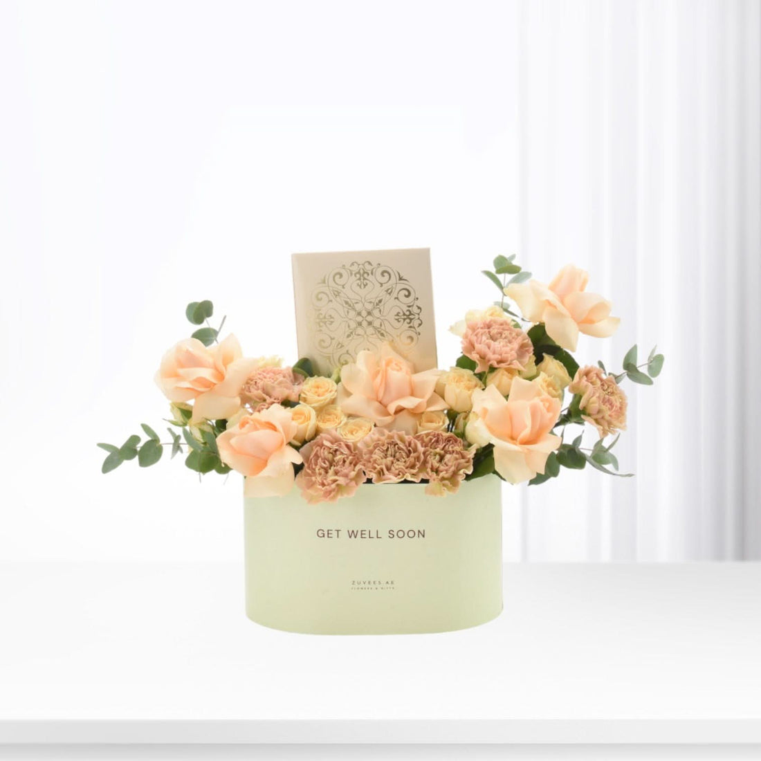 Pastel peach roses and carnations bloom in mint-green “Get Well Soon” box.