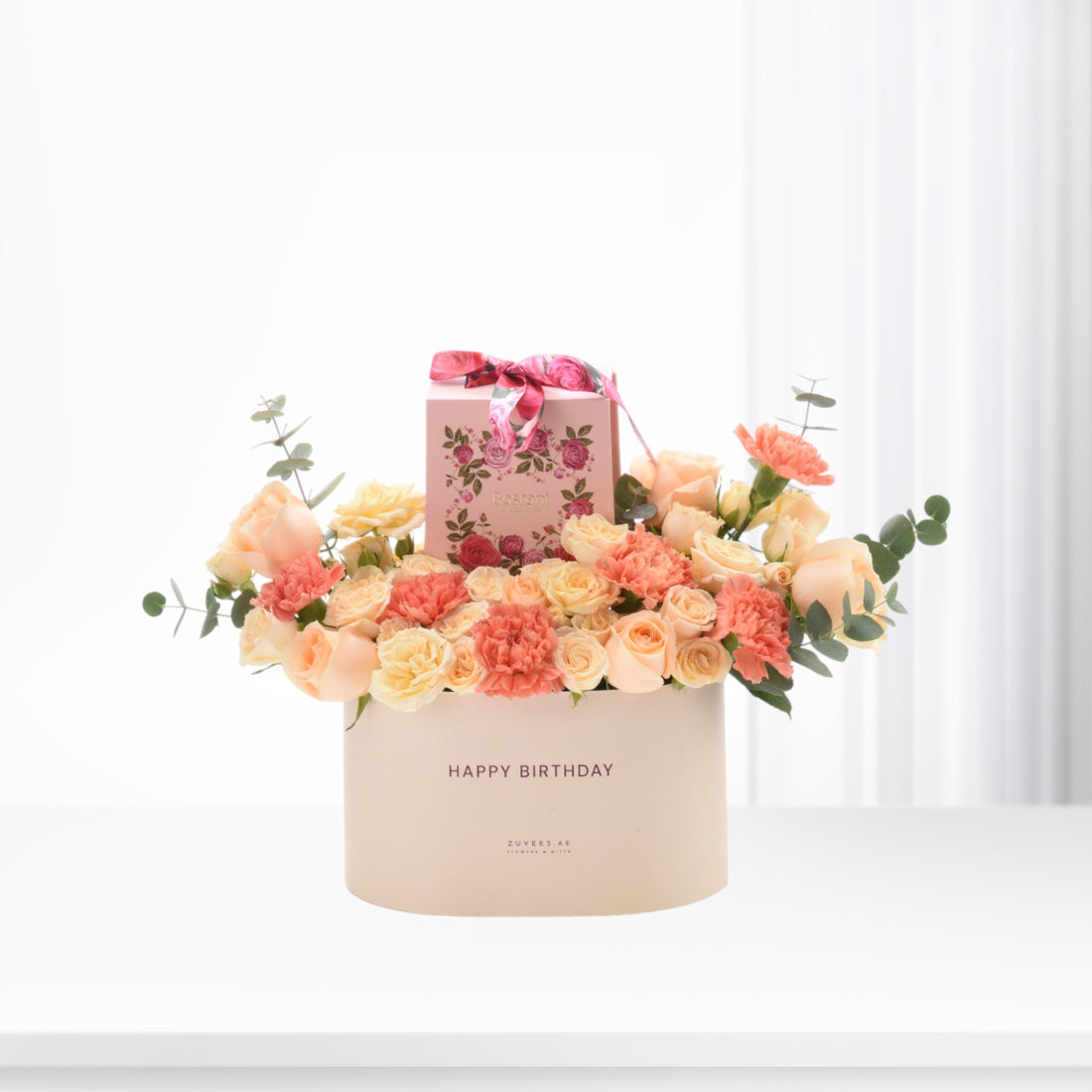 Pastel pink and peach roses with carnations, eucalyptus, and a "Happy Birthday" box.