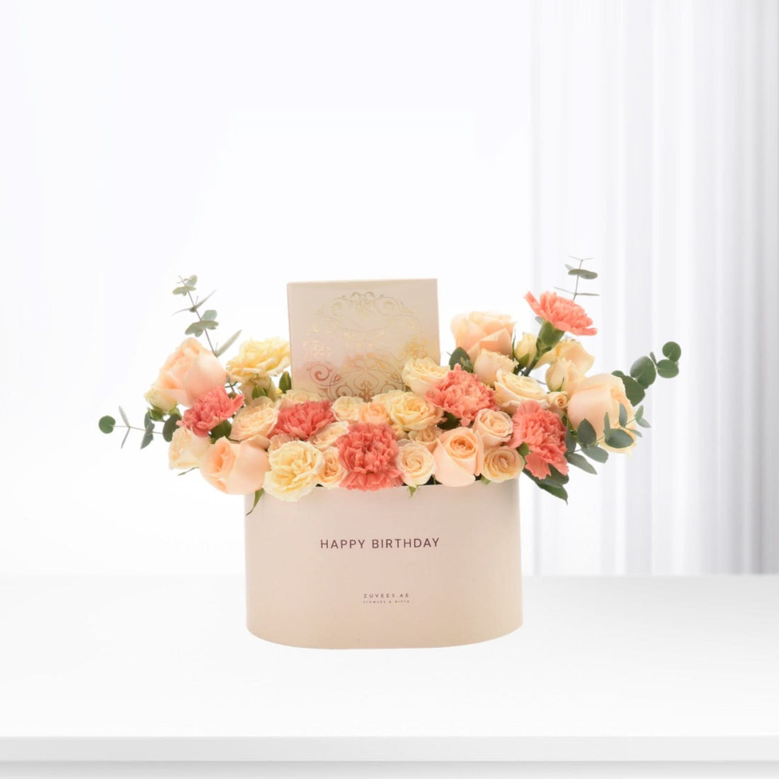 Pastel peach roses and carnations in cream box with "Happy Birthday" message.