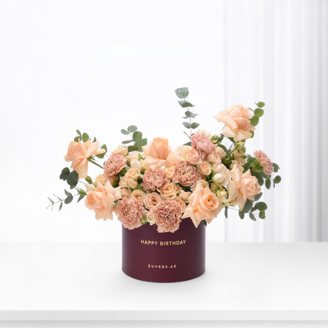 Soft peach roses and carnations in burgundy "Happy Birthday" box.