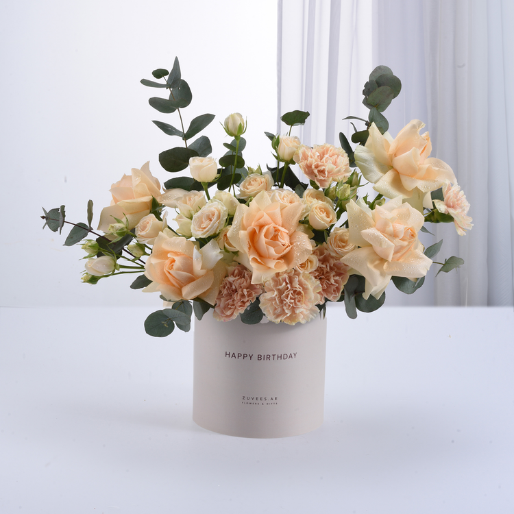 Soft peach roses and carnations in white "Happy Birthday" vase.