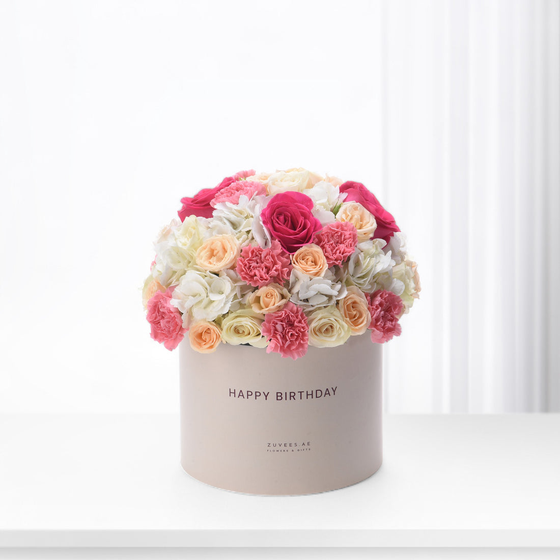 Pink, peach, and white roses and carnations in a beige "Happy Birthday" box.