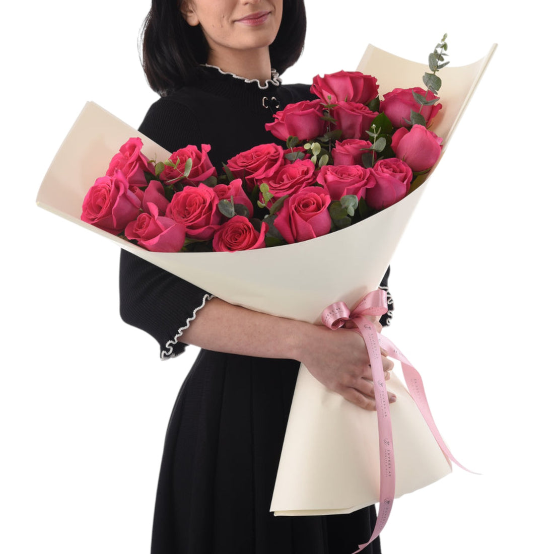 Vibrant pink roses wrapped in cream paper, tied with pink ribbon.