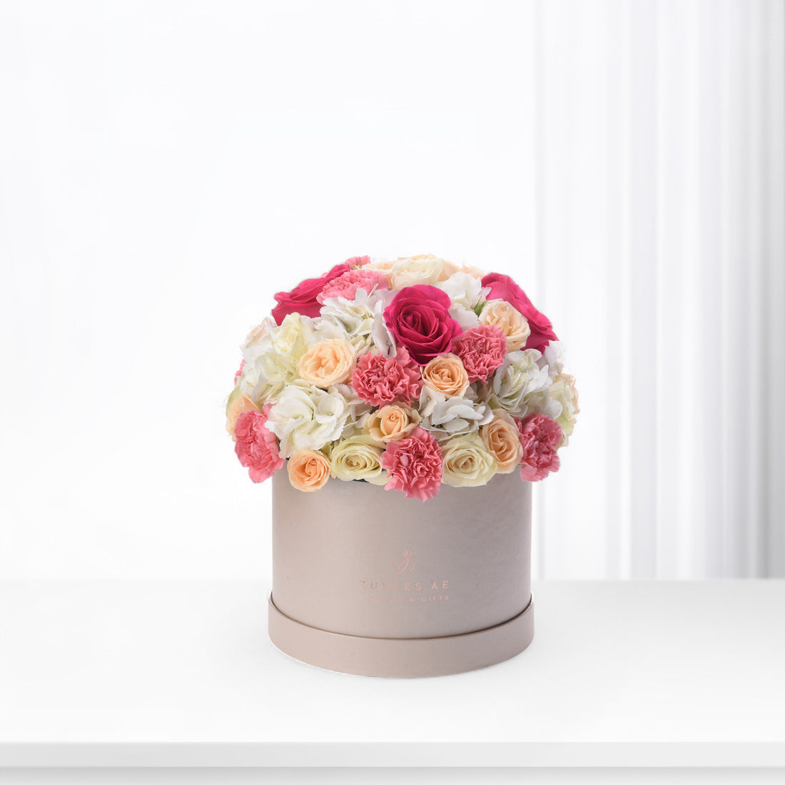 Pink, peach, and white roses and carnations in matte beige box.