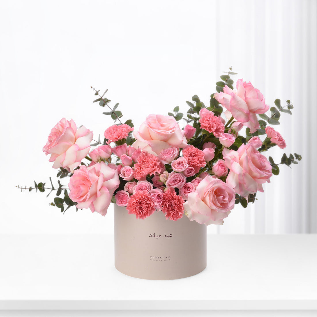 Elegant pink rose and carnation bouquet in minimalist beige box.