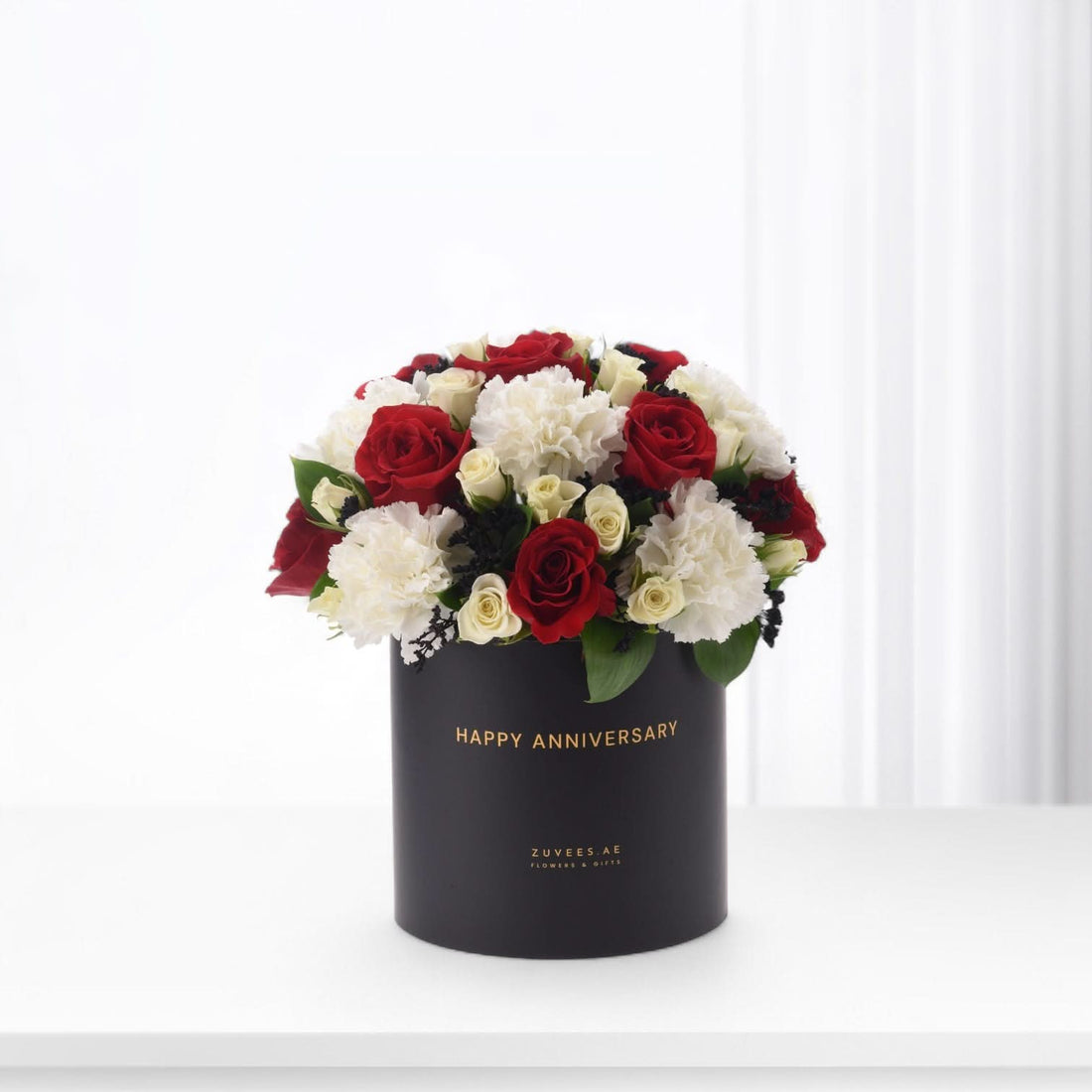 Elegant black box with "Happy Anniversary" holds red roses and white carnations.
