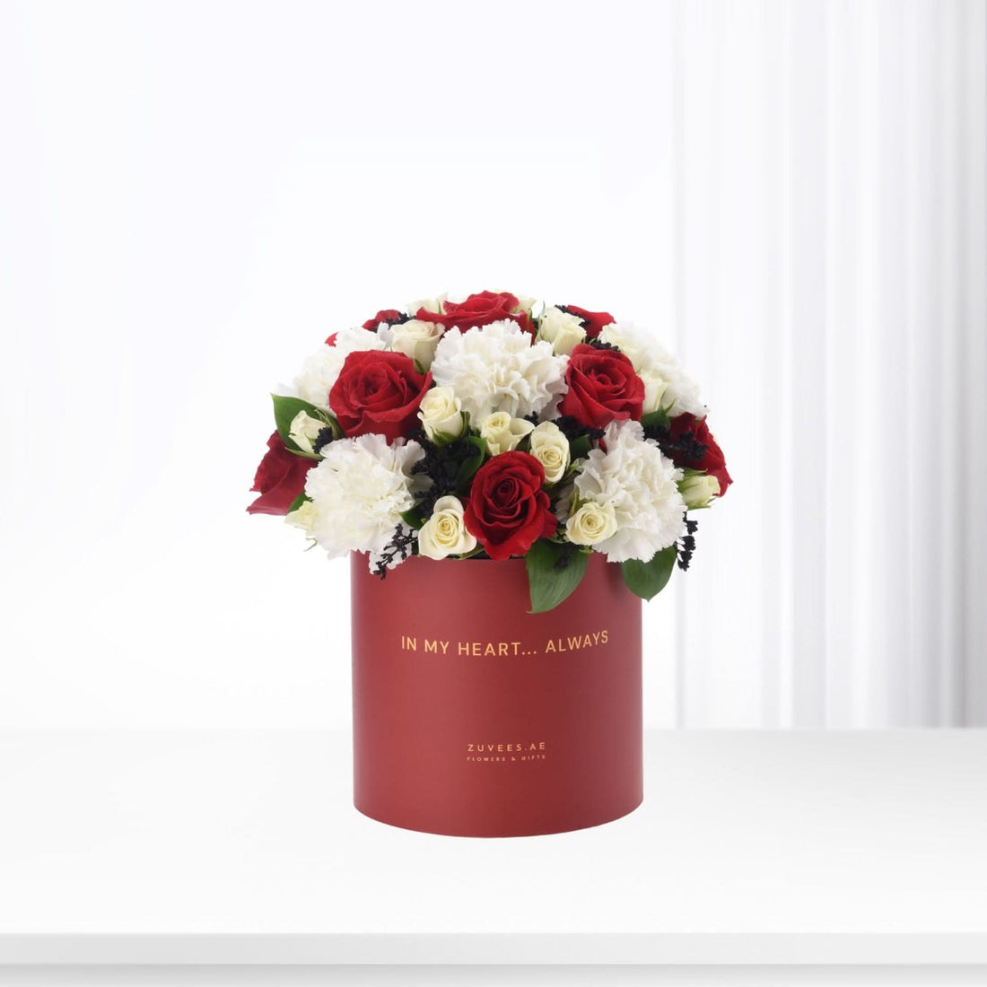 Red velvet box holds vibrant red roses and white carnations, elegant gift for love.