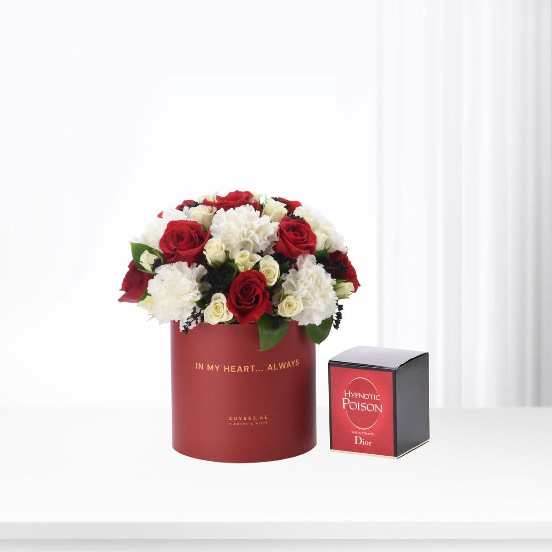 Red and white roses in a red box with "In My Heart... Always" text, beside Dior Hypnotic Poison perfume.